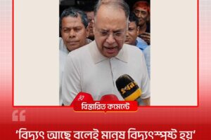 Man in light-colored traditional shirt speaks to reporters, microphones in front of him
